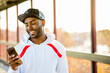 © Adam Hester/Blend Images - Smiling Black man texting on cell phone
