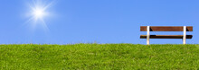 Field With Green Grass And Bench On Sky Background