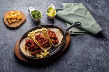 Tacos al pastor on hot skillet ready to prepare with the ingredients of your choice.