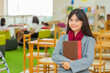 © shine - Smiling asian woman holding books and Prepare to teach in library. Selective focus and Copy space