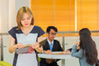 © shine - Happy relaxed confident young school teacher holding books in classroom.