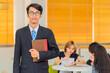 © shine - Happy relaxed confident young school teacher holding books in classroom.