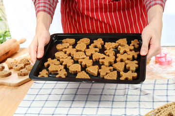 Bakery man holding tray of Christmas gingerbread cookies, homemade cookies before baking, making Xmas ginger bread, preparing bakery, process of baking and cooking at home