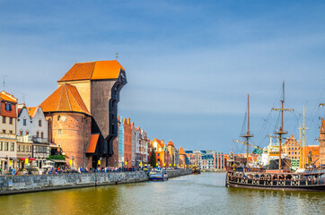 Wall Mural - Gdansk cityscape with Zuraw Crane building and typical colorful houses at Long Bridge embankment promenade, medieval wooden ship on Motlawa river water in historical town centre, Pomerania, Poland