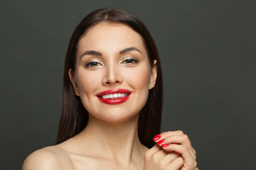 Pretty model woman brunette with makeup and red manicured nails on black background