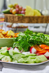 Wall Mural - Sliced salad of cucumbers, tomatoes, radishes and herbs on a plate on a served table. Healthy eating.