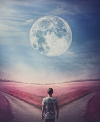 Choose the correct way, left or right. Decisive choice concept. Surreal purple world with a person following the full moon, arrives in front of a crossroad. Split pathway with two directions