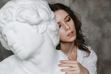 beautiful curly girl sitting hugging with a plaster statue