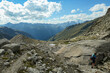 © Chris - Panoramic view from Hohe Sonnblick in Austrian Alps on Gro?glockner.  A woman with hiking backpack hiking through a narrow pathway through the stony landscape, full of lose stones and boulders.