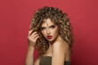 © artmim - Elegant young woman with healthy curly hair on red background