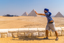 A Young Tourist Joking At The Pyramids Of Giza, The Oldest Funerary Monument In The World. In The City Of Cairo, Egypt