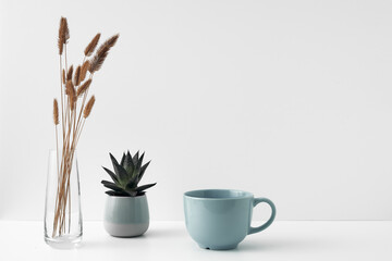 Wall Mural - A mug, a potted houseplant and a transparent vase. Eco-friendly materials in the decor of the room, minimalism. Copy space, mock up