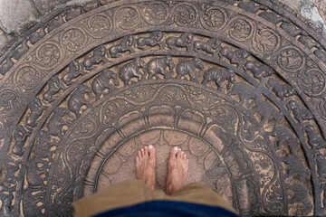 bare feet of the tourist on the stone decoration with patterns and elephants in polonnaruwa temples 