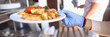 © H_Ko - Female hand in blue medical glove hold white plate with fried potatoes and stewed vegetables. Self service restaurant with tray.