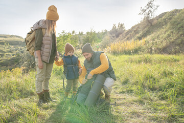 Poster - Young couple and their cute little son with backpacks going to have some rest