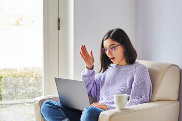 surprised young ethnicity woman with glasses looking in computer a. Lockdown news, online shopping low price