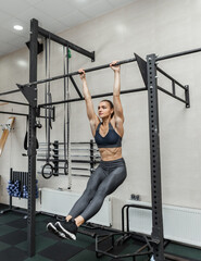 Wall Mural - Functional training. Young fit woman working out on the horizontal bar in the gym