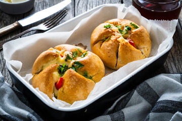 Breakfast - baked stuffed bun with mozzarella ham and red pepper vegetables on wooden table
