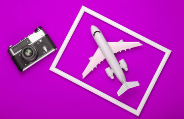 Canvas Print - Retro camera and airplane in a white frame on pink background. Travel concept. Top view. Flat lay