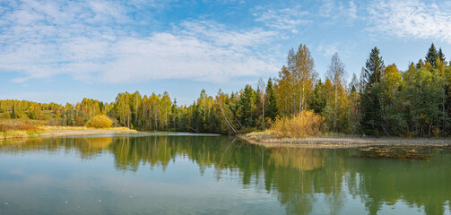 Wall Mural - autumn forest trees are reflected in the river water of the panoramic landscape. blue sky with cloud