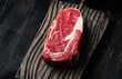 Raw ribeye beef steak on a wooden cutting board . Top view. 
