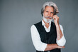 © standret - Against grey background. Stylish modern senior man with gray hair and beard is indoors