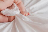 Fototapeta Zwierzęta - close-up of a child's hands lying on a bed covered with a white sheet