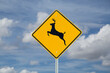 Deer crossing sign on blue sky background (North American road sign)