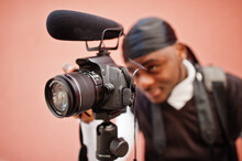 Young Professional African American Videographer Holding Professional Camera With Pro Equipment. Afro Cameraman Wearing Black Duraq Making A Videos.