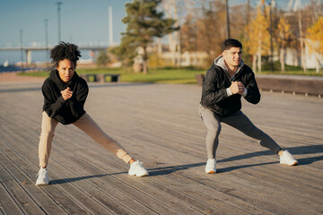 Wall Mural - friends trainers muscle stretching Man and woman African American in sports comfortable clothing for aerobics fitness training on the waterfront in the city. couple playing sports in the Park