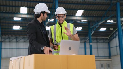 Two factory workers working and discussing manufacturing plan in the factory . Industry and engineering concept .