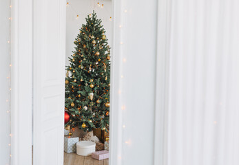 Wall Mural - Decorated Christmas tree in golden and white toys with the gift boxes from door at the bright interior, textured background