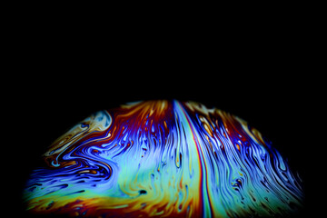 Wall Mural - macro picture of half soap bubble on black ground look like abstract psychedelic color planet in spa