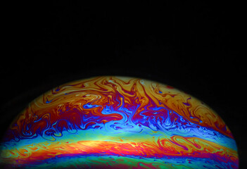 Wall Mural - macro picture of half soap bubble on black ground look like abstract psychedelic color planet in spa