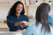 Smiling African American woman shake hand of couple clients at business meeting in office. Back view of recruiters handshake biracial female candidate get acquainted or close deal at negotiation.