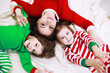 © alexkich - A family in striped pajamas is resting at home. Little children dressed as elves are lying on the sofa. Happy family.
