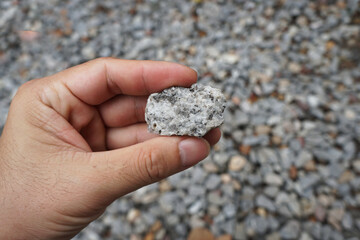 Hand holding a piece of pegmatite granite rock. Igneous Rock Specimen.