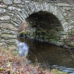 Old stone arch bridge over a stream 