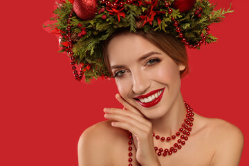 Poster - Beautiful young woman wearing Christmas wreath on red background, closeup