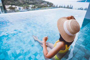 Wall Mural - Asian travel bikini woman relax in infinity pool on phuket beach Thailand