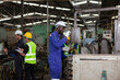 © amorn - Multi-ethnic factory worker working together in the industrial factory while wearing safety uniform, gloves and hard hat