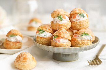 A traditional French savory choux dough cheese puff filled with fresh cheese mixed with smoked salmon in a plate decoration with dill leaf. This pastry well know as spiciality of Burgundy