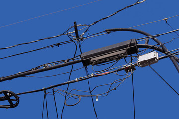 Close-up view of electric distribution wires and cables and devices in the air under blue sky