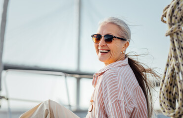 laughing mature woman wearing sunglasses and looking at camera. smiling female in casuals enjoying v