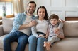 © fizkes - Portrait of happy young Caucasian family with little preschooler son sit relax on sofa in living room. Smiling parents mom and dad rest on couch at home, enjoy weekend together with small boy child.