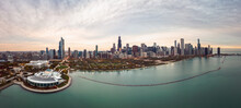 Wide Angle Chicago City Skyline Aerial Panorama With Lake Michigan In The Foreground Overlooking Grant Park And Highrise Skyscraper Buildings With A Beautiful Orange And Blue Sunset Sky Above.
