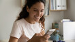 © fizkes - Close up smiling woman looking at phone screen, reading good news in message, happy young female chatting or shopping online, browsing mobile device apps, having fun, enjoying leisure time