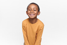 Positive Emotions, Joy And Happy Childhood. Adorable Black Boy Posing Against Blank White Copy Space Studio Wall Background, Looking At Camera With Broad Cheerful Smile, Anticipating Holidays