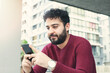 © busra - Cheerful handsome guy with talking on smartphone while sitting