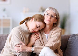 Wall Mural - Sad daughter resting on shoulder of mother.